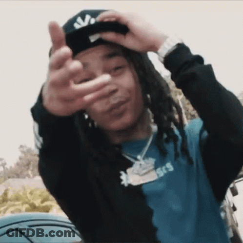 A Young Man With Dreadlocks Is Wearing A Hat And Making A Peace Sign GIF