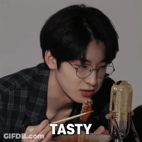 A Young Man With Glasses Is Eating Food With Chopsticks And The Word Tasty Is On The Bottom GIF