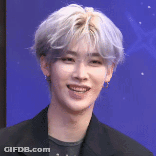 A Young Man With Gray Hair Is Smiling And Wearing A Black Jacket And Earrings . GIF