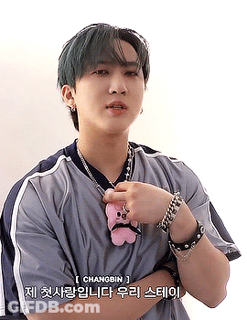 A Young Man With Green Hair Is Wearing A Necklace And Bracelets While Holding A Stuffed Animal . GIF