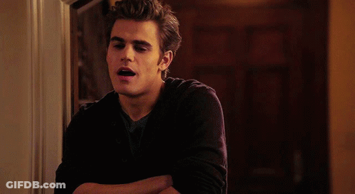 A Young Man With His Arms Crossed Is Leaning Against A Wall GIF