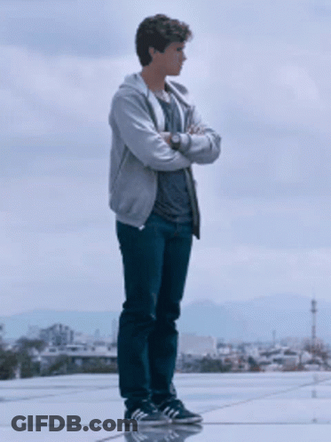 A Young Man With His Arms Crossed Stands On A Rooftop GIF