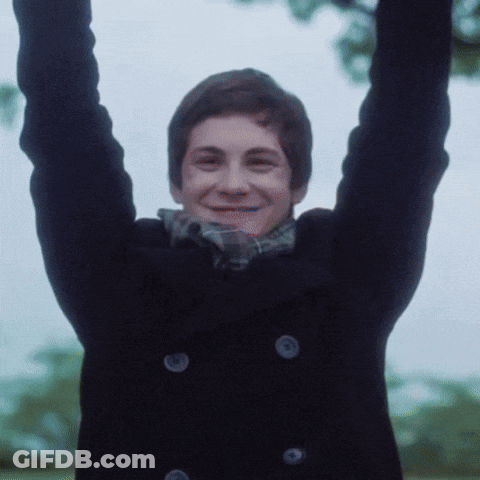 A Young Man With His Arms In The Air Is Wearing A Black Coat GIF