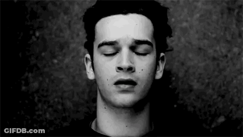 A Young Man With His Eyes Closed In A Black And White Photo . GIF