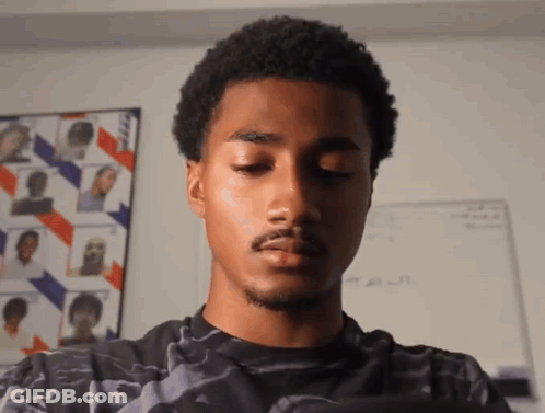 A Young Man With His Eyes Closed Is Standing In Front Of A White Board With A Picture Of A Man On It GIF
