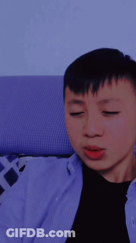 A Young Man With His Eyes Closed Is Wearing A Blue Shirt GIF