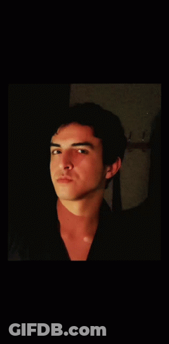 A Young Man With His Eyes Closed Looks At The Camera GIF
