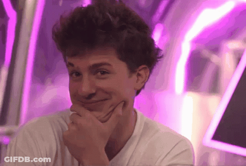 A Young Man With His Hand On His Chin Looks At The Camera GIF