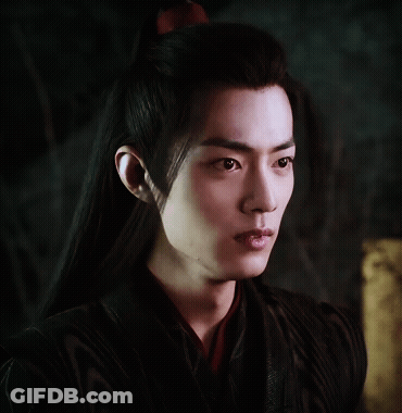 A Young Man With Long Black Hair And A Red Bow In His Hair GIF