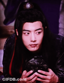 A Young Man With Long Black Hair Is Holding A Fan In His Hands GIF