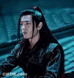 A Young Man With Long Black Hair Is Wearing A Black Jacket And A Red Ponytail . GIF