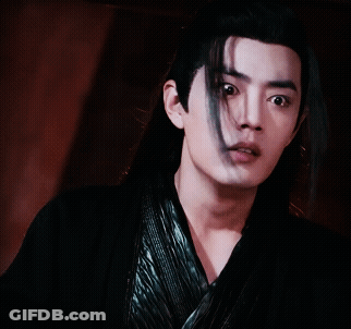 A Young Man With Long Black Hair Is Wearing A Black Shirt GIF