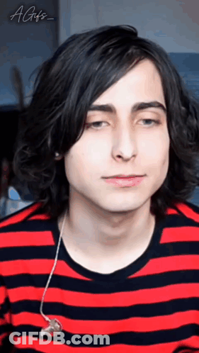 A Young Man With Long Black Hair Is Wearing A Red And Black Striped Shirt And Ear Buds . GIF