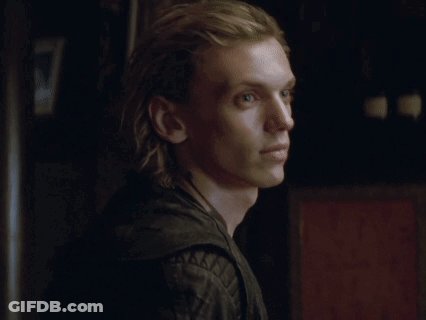 A Young Man With Long Blonde Hair Is Wearing A Black Leather Jacket And A Necklace . GIF