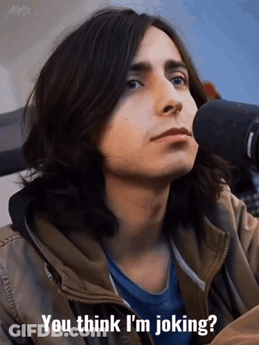 A Young Man With Long Hair Is Sitting In Front Of A Microphone And Says " You Think I 'M Joking " GIF
