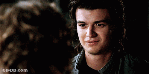 A Young Man With Long Hair Is Smiling While Looking At A Woman . GIF