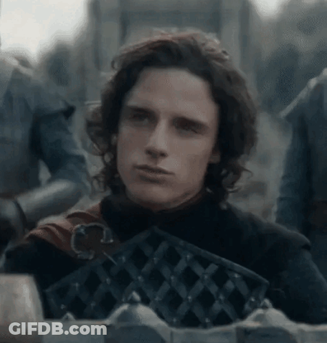 A Young Man With Long Hair Is Standing In Front Of A Fence Holding A Sword . GIF