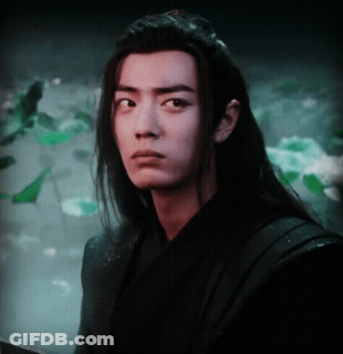 A Young Man With Long Hair Looks At The Camera GIF