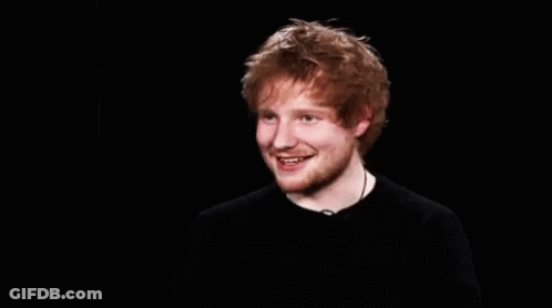 A Young Man With Red Hair And A Beard Is Smiling In A Black Shirt . GIF
