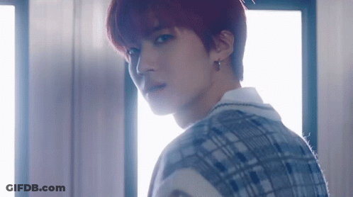 A Young Man With Red Hair And A Plaid Vest Is Standing In Front Of A Window . GIF