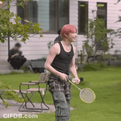 A Young Man With Red Hair Is Holding A Badminton Racquet GIF