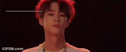 A Young Man With Red Hair Is Standing In Front Of A Black Background And The Name Ayno Is Written Above Him . GIF