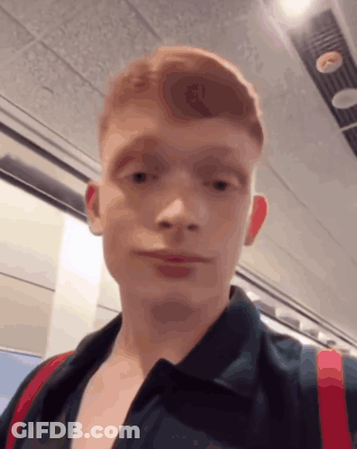 A Young Man With Red Hair Is Wearing A Black Shirt GIF