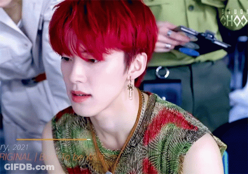 A Young Man With Red Hair Is Wearing Earrings And A Shirt That Says Studio Chax GIF