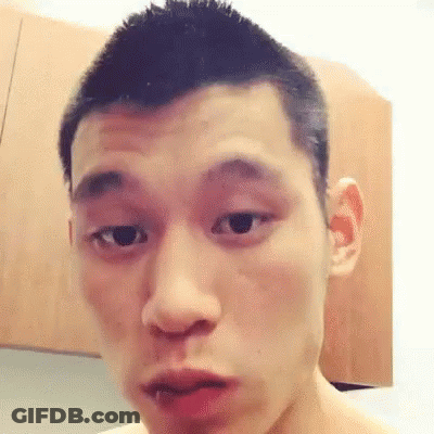 A Young Man With Short Hair Is Making A Funny Face In Front Of A Wooden Cabinet . GIF