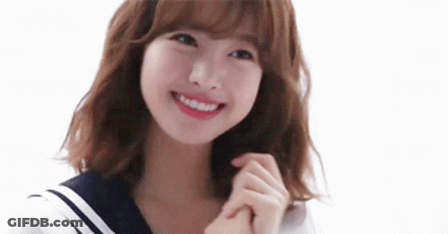 A Young Woman In A Sailor Suit Is Smiling And Holding Her Hands Together . GIF