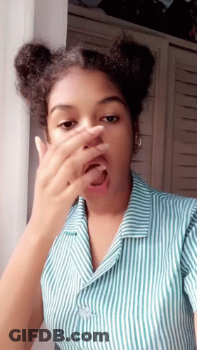 A Young Woman In A Striped Shirt Is Covering Her Face With Her Hand . GIF