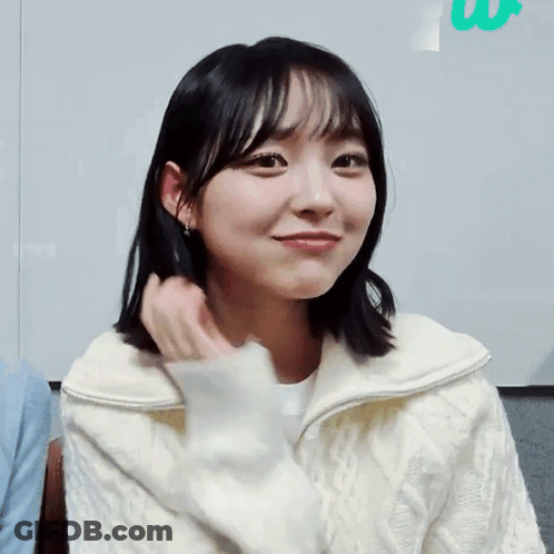 A Young Woman In A White Sweater Is Smiling GIF