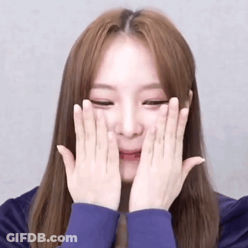 A Young Woman Is Covering Her Face With Her Hands . GIF
