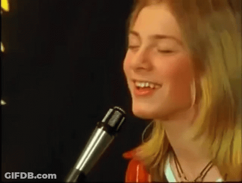 A Young Woman Is Singing Into A Microphone With Her Eyes Closed . GIF