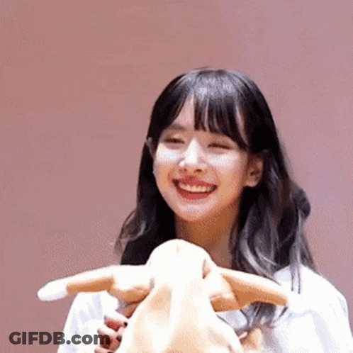 A Young Woman Is Smiling While Holding A Stuffed Animal . GIF