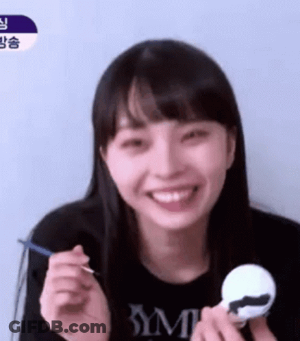 A Young Woman Is Smiling While Holding A Toy And A Spoon In Her Hand . GIF