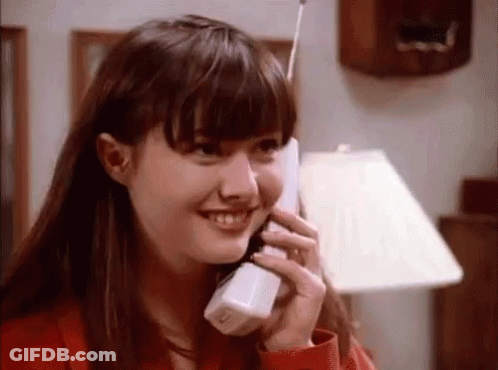 A Young Woman Is Smiling While Talking On A Cell Phone . GIF