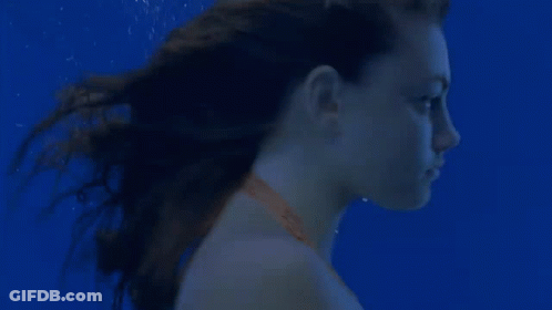 A Young Woman Is Swimming Underwater In A Pool . GIF
