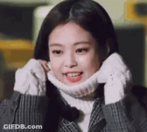 A Young Woman Wearing A Turtleneck Sweater And Gloves Is Smiling . GIF