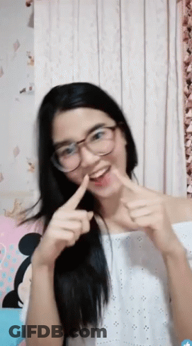 A Young Woman Wearing Glasses And A White Top Is Making A Funny Face GIF