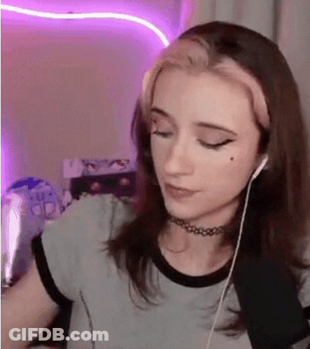 A Young Woman Wearing Headphones And A Choker Is Sitting In Front Of A Computer . GIF