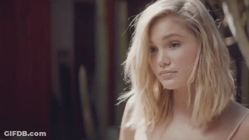 A Young Woman With Blonde Hair Is Looking At The Camera . GIF