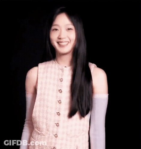 A Young Woman With Long Black Hair Is Wearing A Pink Dress And Purple Gloves And Smiling . GIF