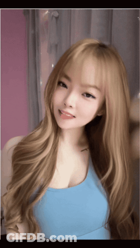 A Young Woman With Long Blonde Hair Is Wearing A Blue Tank Top GIF