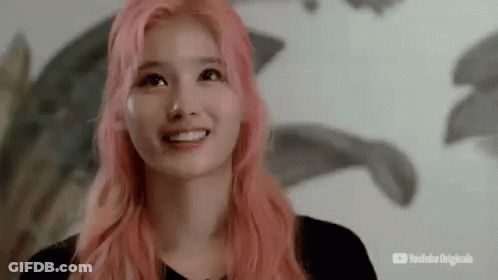 A Young Woman With Pink Hair Is Smiling And Looking Up . GIF