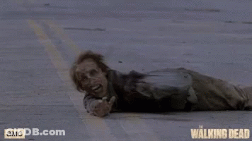 A Zombie Is Laying On The Ground With A Walking Dead Logo In The Background GIF
