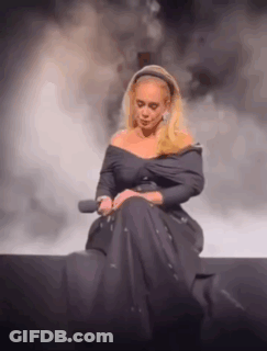 Adele Is Sitting On A Stage With A Microphone In Her Hand . GIF