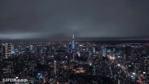 Aerial View Of City At Night With Blue Skyscraper GIF