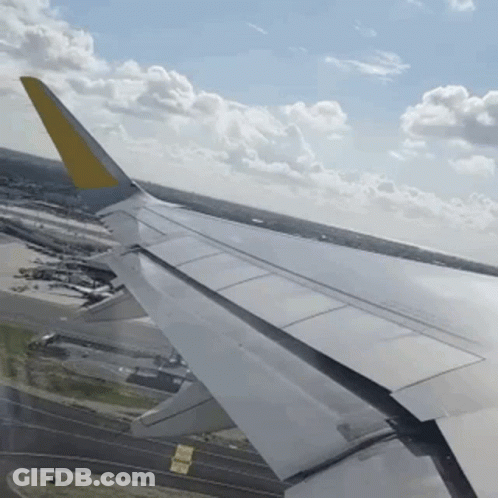 Airplane Wing With Yellow Tail Over Runway GIF
