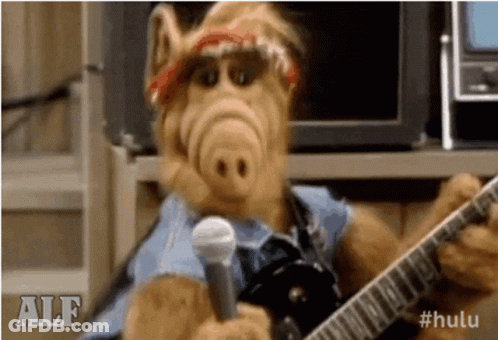 Alf From The Simpsons Is Holding A Guitar And A Microphone . GIF